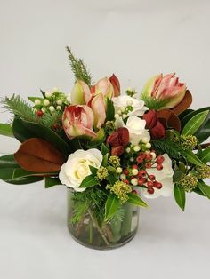 a glass vase filled with flowers and greenery