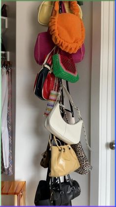 a bunch of purses hanging from a hook on a wall in a room with white walls