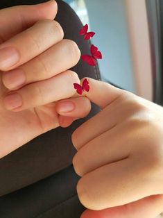 a woman's hand with red flowers on her fingers and the tip of her finger