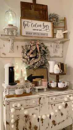 an old dresser is decorated for christmas with white ornaments and coffee mugs on it