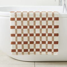 a brown and white checkered towel hanging on the side of a bath tub