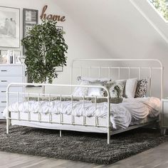 a white bed sitting in a bedroom next to a dresser and window on top of a wooden floor