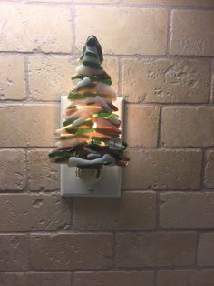 a christmas tree made out of candles on a brick wall mounted light switch cover in the shape of an ornament