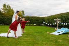 a bride and two flower girls playing in the yard with an obstacle set up behind them