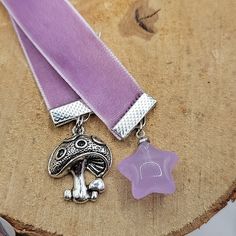 a purple ribbon with two charms attached to it sitting on top of a piece of wood