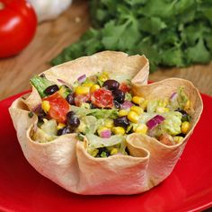 a red plate topped with burritos filled with veggies and salsa next to tomatoes