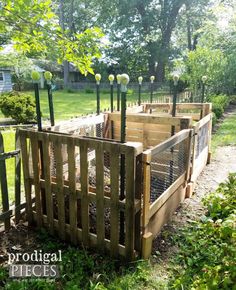 several wooden crates with plants growing out of them in the middle of some grass and trees