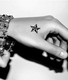 black and white photograph of two hands holding each other with tattoos on their wristes