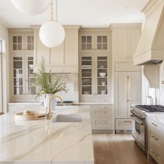 a large kitchen with marble counter tops and white cabinets, along with an island in the middle