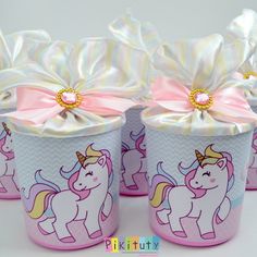 four pink cups with unicorns painted on them and ribbons tied around the top one