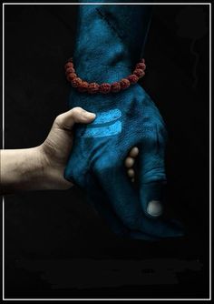 two hands are holding each other with blue paint on their palms and one hand is wearing a red beaded bracelet