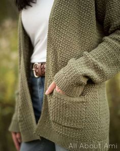 a woman is wearing a green cardigan and pointing to the side with her finger