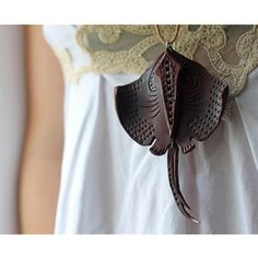 a woman wearing a white shirt and brown leather necklace with an elephant head on it