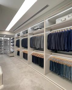 the inside of a clothing store with clothes on racks