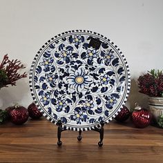 a decorative blue and white plate sitting on top of a wooden table next to potted plants