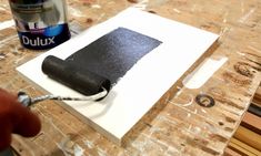 a person is painting a piece of wood with black paint and a roller on it