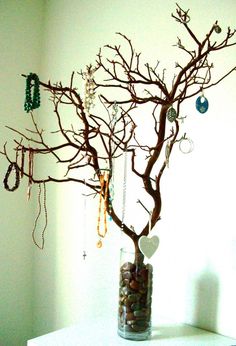 a tree with jewelry hanging from it's branches in a vase on a table