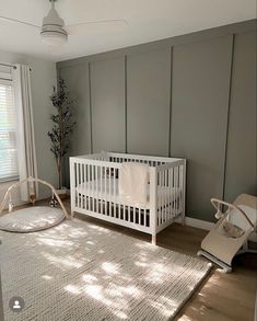 a baby's room with a white crib, rocking chair and large window