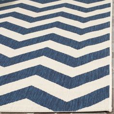 a blue and white chevroned rug sitting on top of a wooden floor next to a brick wall