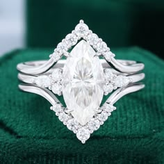 a white diamond ring sitting on top of a green cloth