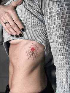 a woman's stomach with a rose tattoo on her left side, and the bottom half of her abdomen