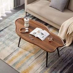 a living room with a couch, coffee table and rug on the floor in front of it