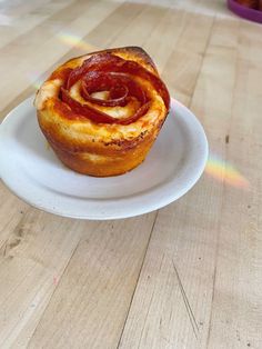 a hot dog in a bun on a white plate sitting on a wooden table top