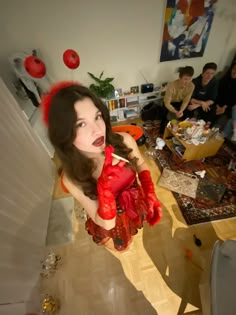 a woman with red gloves on her head in a living room next to other people