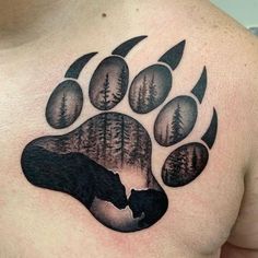 a man's chest with a bear paw tattoo on it and trees in the background