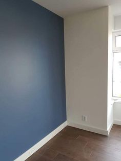 an empty room with blue walls and wood floors