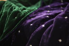 the bed is covered in purple and green sheets with white stars on them as if they were made out of fabric