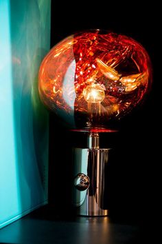 a red lamp sitting on top of a table next to a blue box and wall