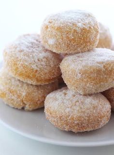 several sugared donuts stacked on top of each other on a white plate with powdered sugar