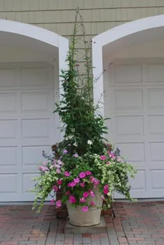 a potted plant with pink and purple flowers in front of two white garage doors