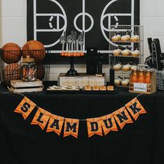 a black table topped with cupcakes and desserts next to a basketball court