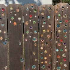 a wooden fence with many different colored glass beads on the top and bottom boards,