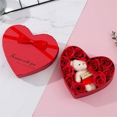 two heart shaped boxes filled with roses and a teddy bear in the middle one has a message on it