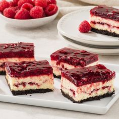 raspberry cheesecake slices on white plates with bowl of raspberries