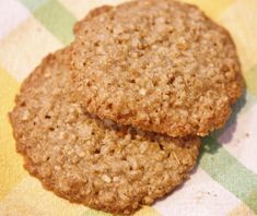 two oatmeal cookies sitting on top of a checkered table cloth with one cookie in the middle