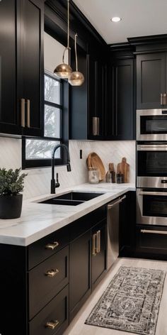 a kitchen with black cabinets and white counter tops, an area rug and potted plant