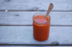 a wooden table with a glass jar filled with sauce and a spoon on top of it