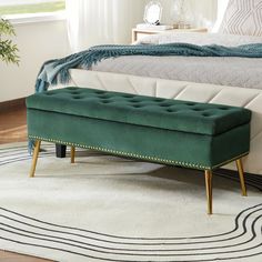 a green bench sitting on top of a rug in front of a bed with white sheets