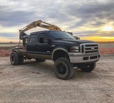 a black truck parked on top of a dirt field