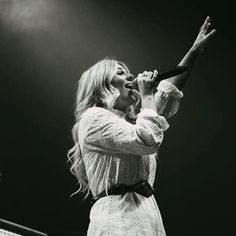 a black and white photo of a woman holding a microphone up to her mouth as she sings