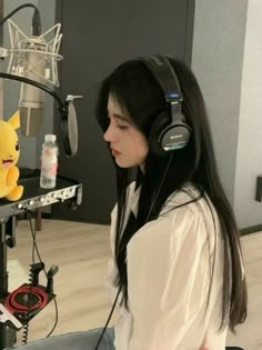 a woman sitting in front of a microphone with headphones on and a pikachu stuffed animal