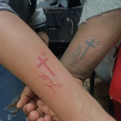 two people holding hands with tattoos on their arms and the words faith written in pink ink