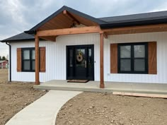 a white house with black doors and brown shutters on the front door is under construction