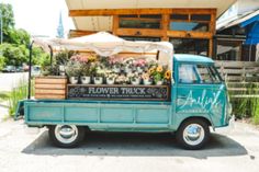 an old blue truck with flowers on the back is parked in front of a building