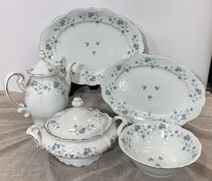 a table topped with lots of white dishes covered in blue flowered designs and saucers