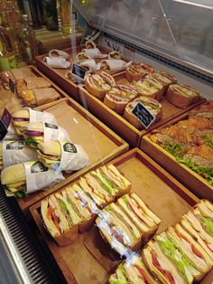 a display case filled with lots of sandwiches and condiments on wooden trays